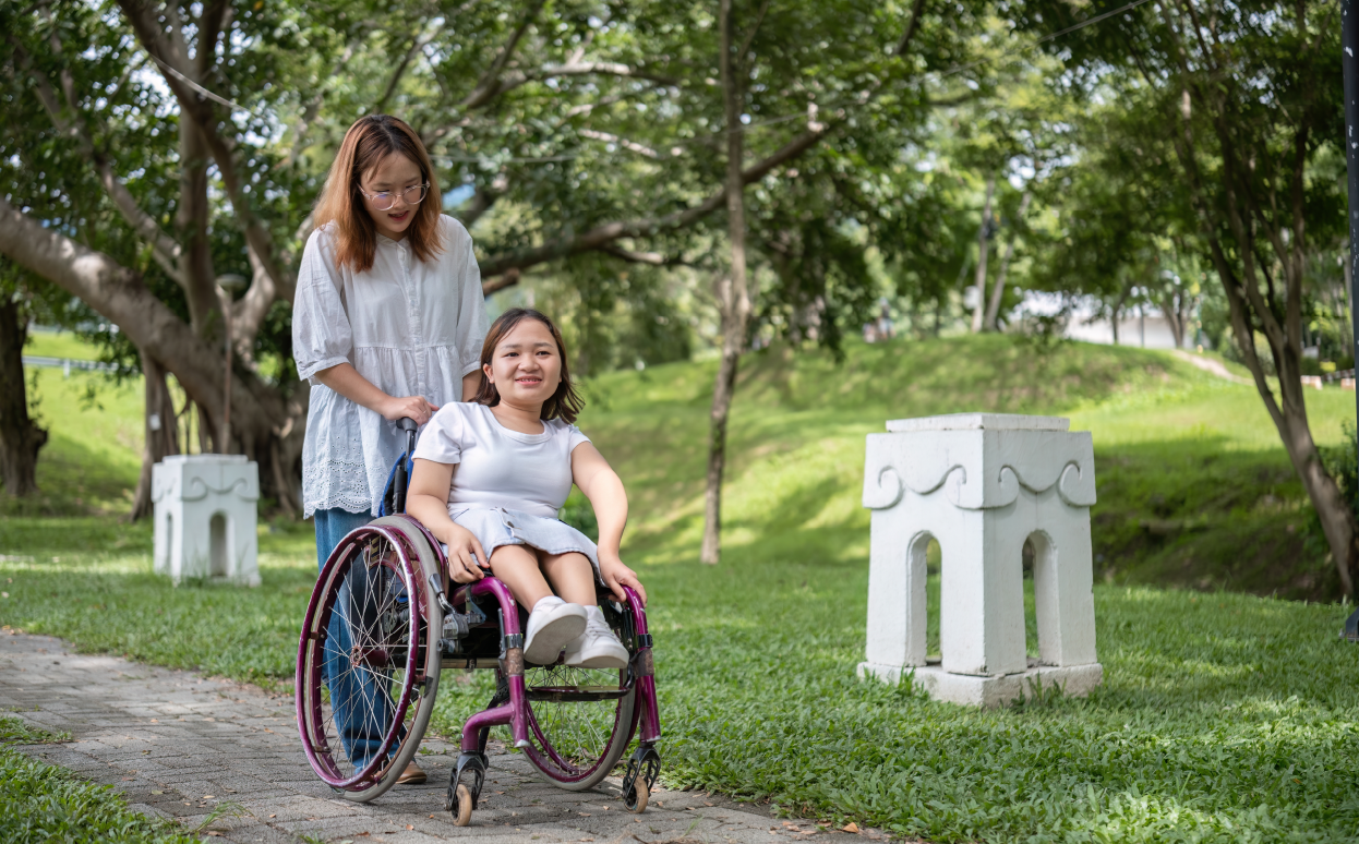 Girl in a wheelchair being helped by a caregiver