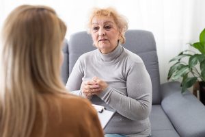 A woman receiving speech therapy, practicing communication exercises with a therapist to improve speech and swallowing abilities